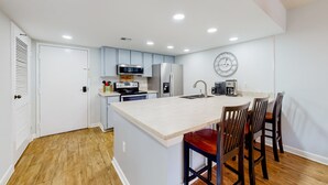 A modern kitchen with a central island, built-in appliances, and a dining area with bar stools.