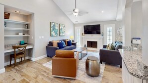 A living room with a fireplace, a television, and a seating area with sofas and a coffee table. - Stunningly remodeled villa with shared pool and golf on-site (Hilton Head)
