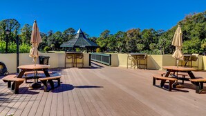 An outdoor patio area with picnic tables and umbrellas, a gazebo, and a view of trees. - Stunningly remodeled villa with shared pool and golf on-site (Hilton Head)