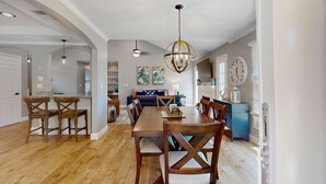 A dining area with a wooden table and chairs, a chandelier, and a clock on the wall. - Stunningly remodeled villa with shared pool and golf on-site (Hilton Head)