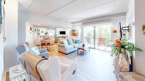 Un amplio espacio habitable con sofá, sillas, una mesa de comedor y una cocina al fondo.