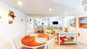 Un espacio habitable moderno con zona de comedor, cocina y un espejo grande que refleja la habitación.