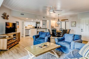 A spacious living room with a television, sofas, and a coffee table. - Villa with pool, tennis courts, & private patio - walk to the beach (Hilton Head)