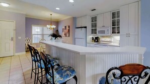 A kitchen with white cabinets, a microwave, and a stove. There is a bar area with stools. - Well-appointed villa with rooftop pool & beach access - 1 block to Coligny Plaza (Hilton Head)