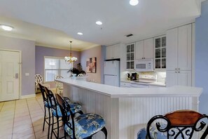 A kitchen with white cabinets, a microwave, and a stove. There is a bar area with stools. - Well-appointed villa with rooftop pool & beach access - 1 block to Coligny Plaza (Hilton Head)