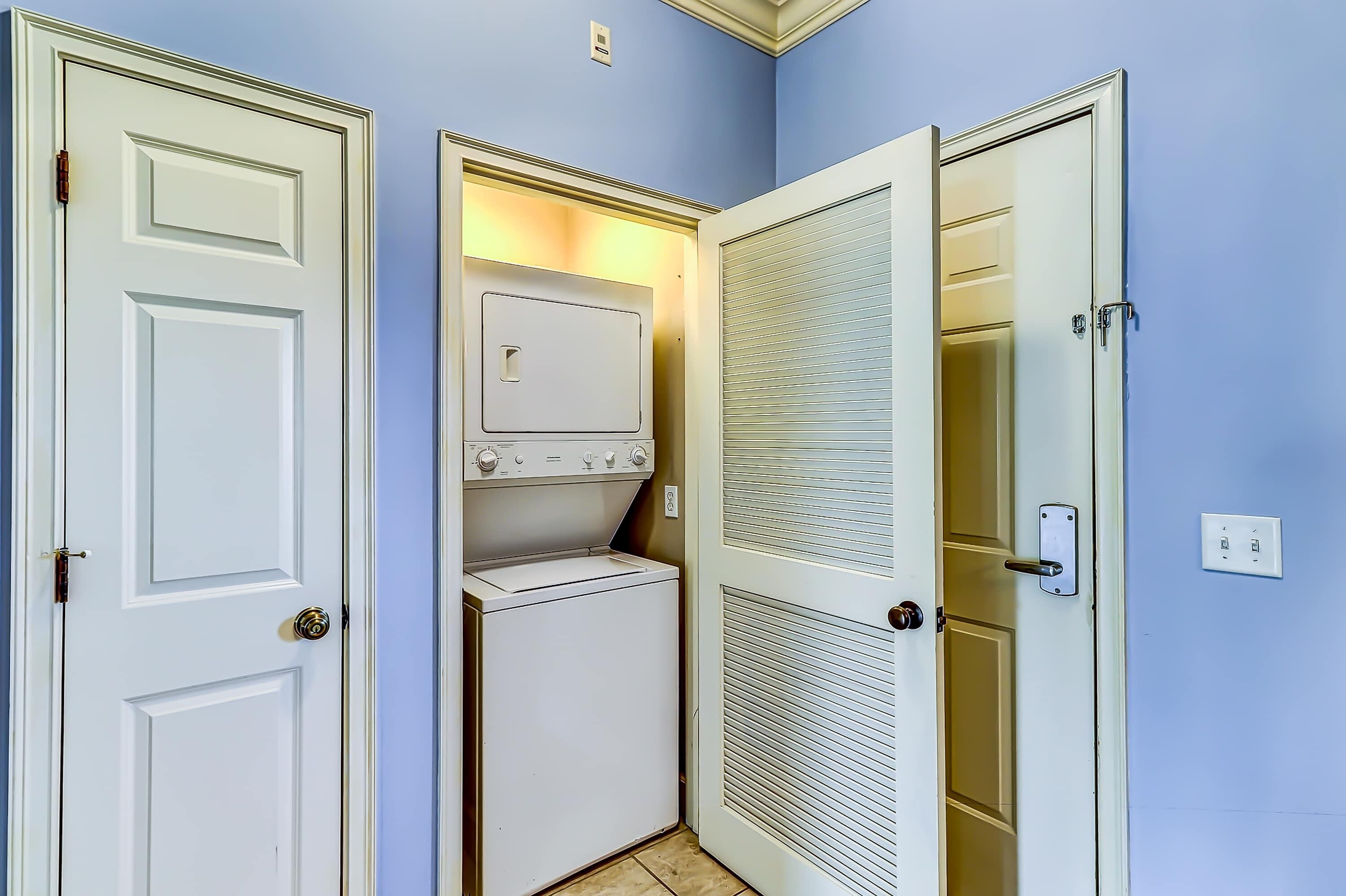 A laundry room with a washer and dryer, a door with a window, and a light switch on the wall.
