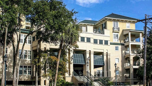 A multi-story building with balconies, a central staircase, and surrounding trees. - Well-appointed villa with rooftop pool & beach access - 1 block to Coligny Plaza (Hilton Head)