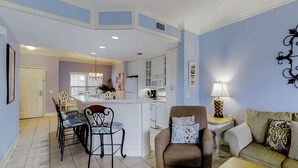 A living room with a sofa, a dining table with chairs, a kitchen area with cabinets, and a central island. - Well-appointed villa with rooftop pool & beach access - 1 block to Coligny Plaza (Hilton Head)