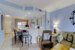 A living room with a sofa, a dining table with chairs, a kitchen area with cabinets, and a central island. - Well-appointed villa with rooftop pool & beach access - 1 block to Coligny Plaza (Hilton Head)