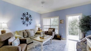 A living room with a sofa, armchairs, a coffee table, a lamp, a decorative wall piece, and a large window with blinds. - Well-appointed villa with rooftop pool & beach access - 1 block to Coligny Plaza (Hilton Head)