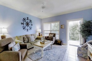 A living room with a sofa, armchairs, a coffee table, a lamp, a decorative wall piece, and a large window with blinds. - Well-appointed villa with rooftop pool & beach access - 1 block to Coligny Plaza (Hilton Head)
