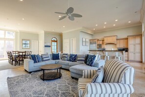 A spacious living area with a sectional sofa, a striped armchair, a coffee table, and a ceiling fan. - Ocean and Marsh View Home with private pool, dog friendly, beachfront (Hilton Head)
