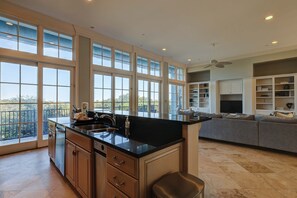 A spacious kitchen with large windows, a central island, and a grey sofa in a living area. - Ocean and Marsh View Home with private pool, dog friendly, beachfront (Hilton Head)
