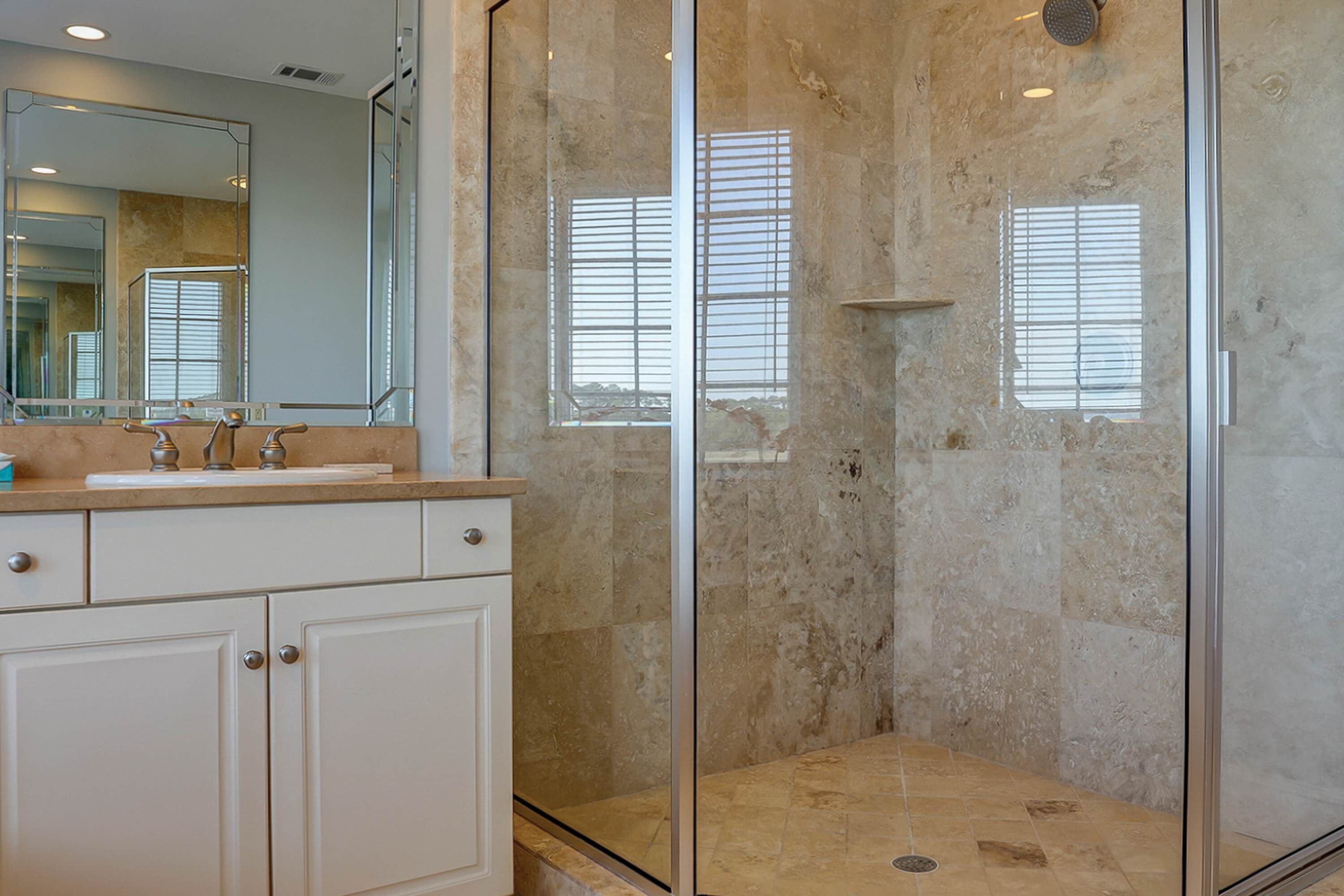 Une salle de bain avec une douche à parois de verre, un grand miroir et un plan de toilette avec un lavabo.