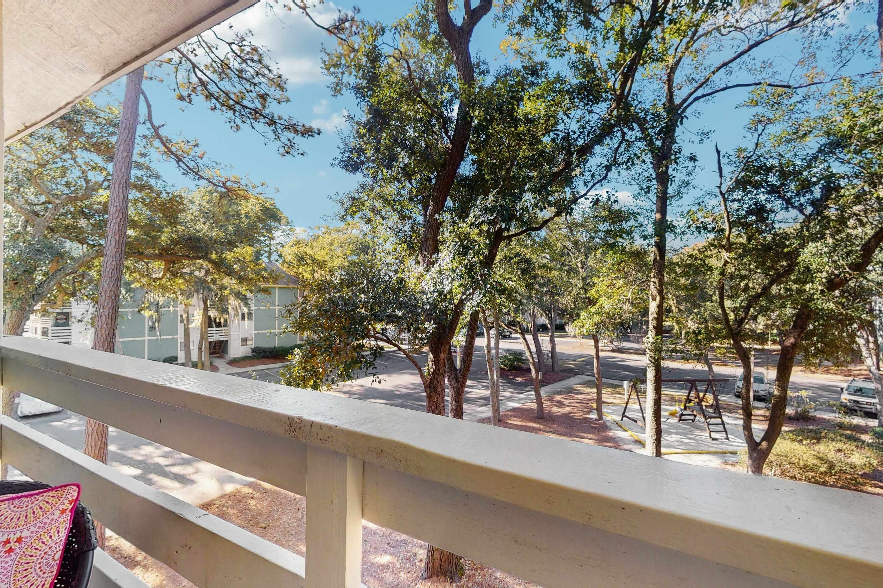 A balcony with a view of trees and a street.