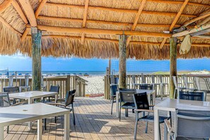 An outdoor patio with tables and chairs, a thatched roof, and a view of the beach. - Snowbird Discounts, Steps to beach, 2 and a half Bathrooms, & Coligny (Hilton Head)