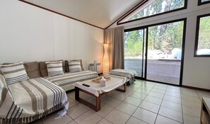 Habitación con sofá, una mesa con bandeja, una lámpara y vistas a través de un ventanal.