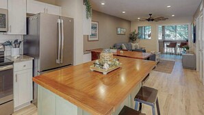 Una cucina moderna con elettrodomestici in acciaio inossidabile, un'isola in legno e un'area pranzo con vista.
