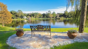 Un banc offrant une vue sur un lac, entouré de pelouse et de plantes en pot.