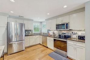 A modern kitchen with stainless steel appliances, white cabinetry, and a wooden floor. - Golf course view condo near walking trails, Van der Meer & Shipyard beach (Hilton Head)