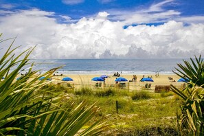 A beach with umbrellas, people, and a view of the ocean. - Golf course view condo near walking trails, Van der Meer & Shipyard beach (Hilton Head)