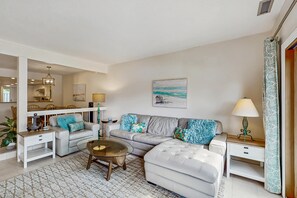 A living room with a sofa, coffee table, and a dining area with a chandelier. - Waterfront condo with private balcony, W D and near beach and marina (Hilton Head)