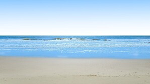 A beach with clear skies and calm waves. - Beachfront condo w pool, tennis and pickleball, gym & balcony (Hilton Head)