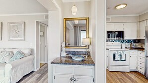 A kitchen with white cabinets, a stove, and a microwave. - Beachfront condo w pool, tennis and pickleball, gym & balcony (Hilton Head)