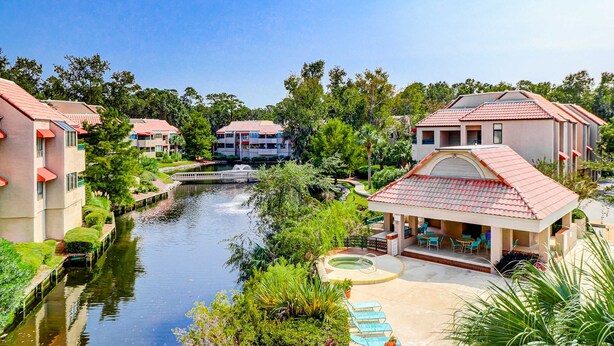 A riverside hotel with a swimming pool, outdoor seating, and a bridge. - Lagoon views, shared pool and easy access to Shelter Cove Towne Center (Hilton Head)