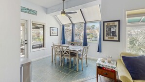 A dining area with a table and chairs, a ceiling fan, and large windows with curtains. - Lagoon views, shared pool and easy access to Shelter Cove Towne Center (Hilton Head)