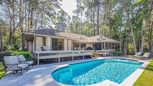 Ein Haus mit Swimmingpool, Sitzgelegenheiten im Freien und einer überdachten Terrasse.