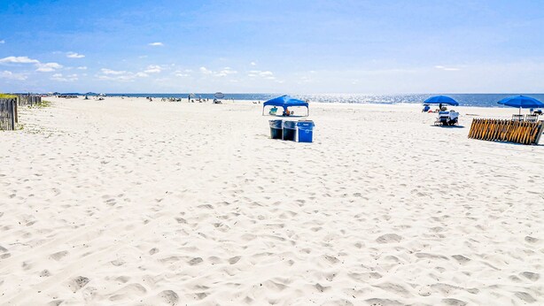 Een zandstrand met blauwe parasols en ligstoelen.