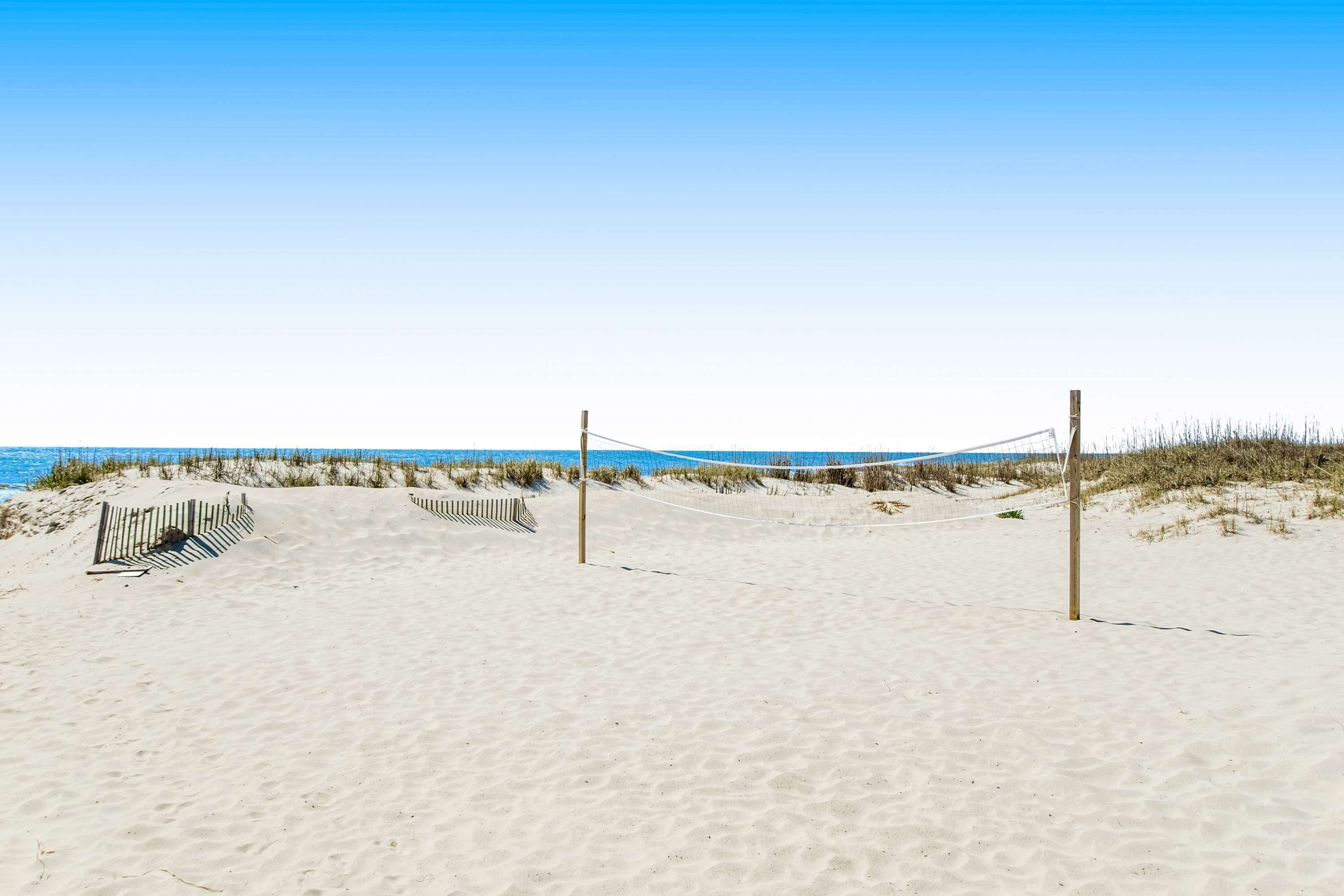 Ein Strand mit Volleyballnetz, Sand und Dünen.