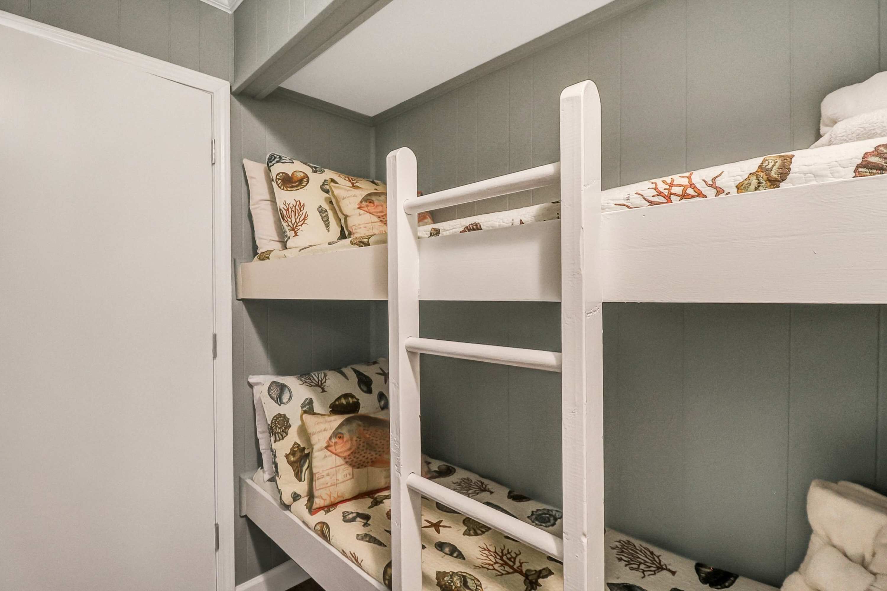 A bunk bed with patterned bedding and a white wardrobe.