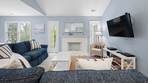 Ein Wohnzimmer mit einer Couch, einem Couchtisch, einem Kamin, einem Fernseher und einem Bücherregal.