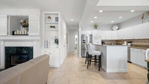 Une cuisine moderne avec des meubles blancs, un îlot central et une cheminée.