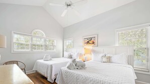 Une chambre d’hôtel avec deux lits, un bureau et un ventilateur de plafond.