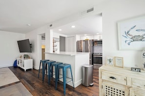 A modern kitchen with a central island, bar stools, a stainless steel refrigerator, and a trash can. - Beautiful updated condo- On-site pool, blocks from beach and Coligny Plaza (Hilton Head)