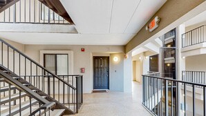 Un interior de varios niveles con una escalera, una puerta con una luz circular y un detector de incendios.