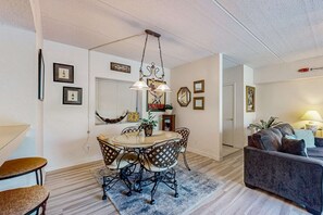 A dining area with a round table, chairs, and a hanging light fixture. - Close to beach with pool, tennis, pool  & private balcony (Hilton Head)