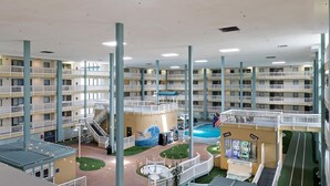 A multi-level hotel atrium with balconies, a pool, and a game room. - Beach condo with balcony, pools, & hot tub- near golf & beach (Hilton Head)