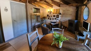 Un intérieur rustique avec des poutres apparentes, une cheminée, une table à manger avec des chaises et une porte blanche.