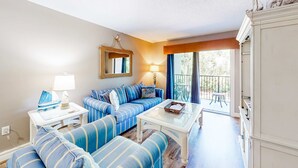 Un salon comprenant un ensemble de canapés, une table basse, une lampe, un miroir et une vue sur l’extérieur.