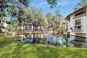 Un complex turístic amb una bassa, arbres i edificis amb balcons.