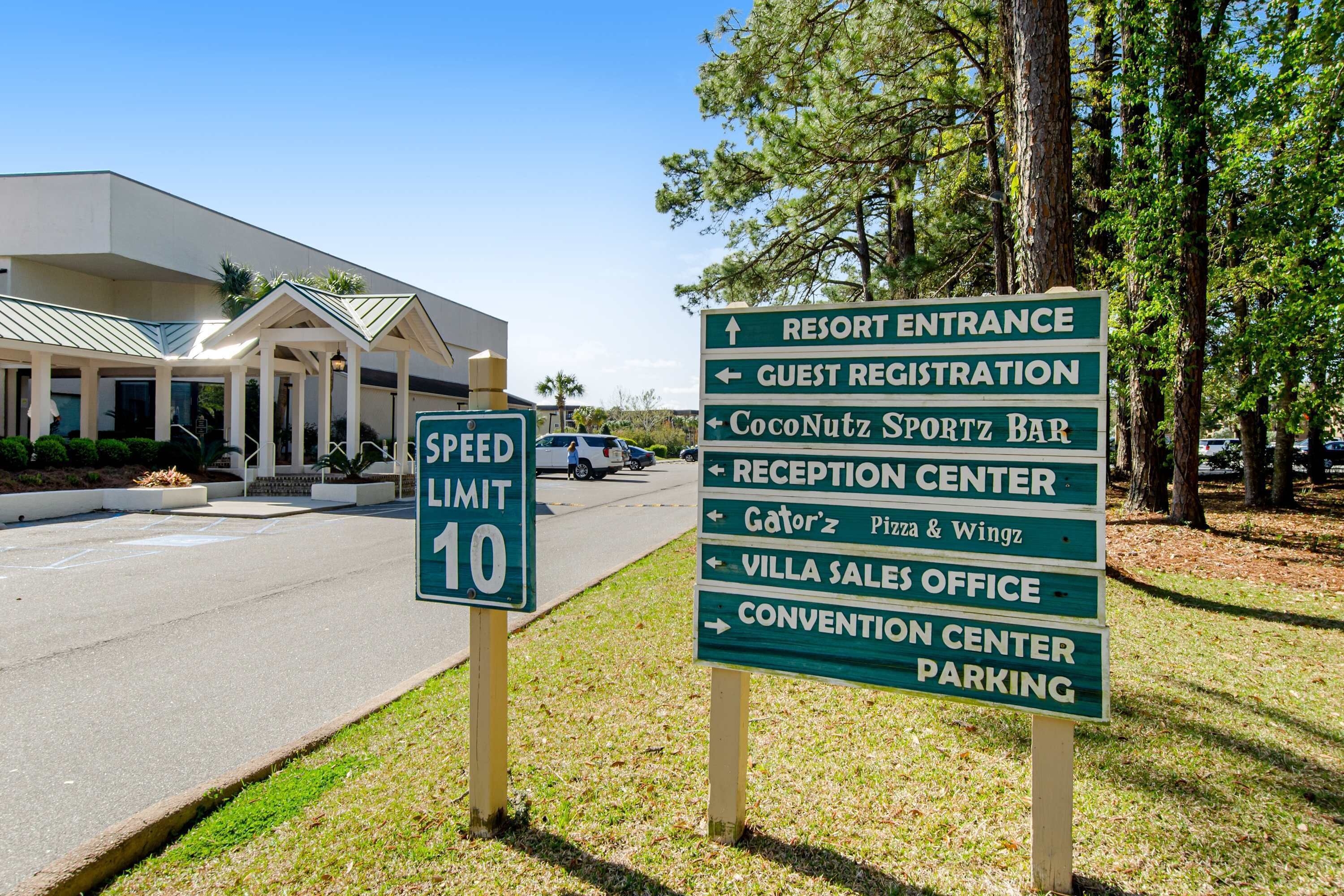 A speed limit sign and directional signs for a resort, including the guest registration, reception center, and parking areas.