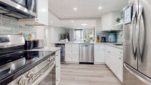 Een moderne keuken met roestvrijstalen apparatuur, witte kasten en een betegelde achterwand.