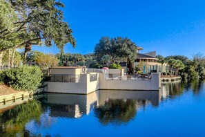 Ein Anwesen am Wasser mit Pool, ein Haus mit gewölbtem Dach und umgebender Bepflanzung.