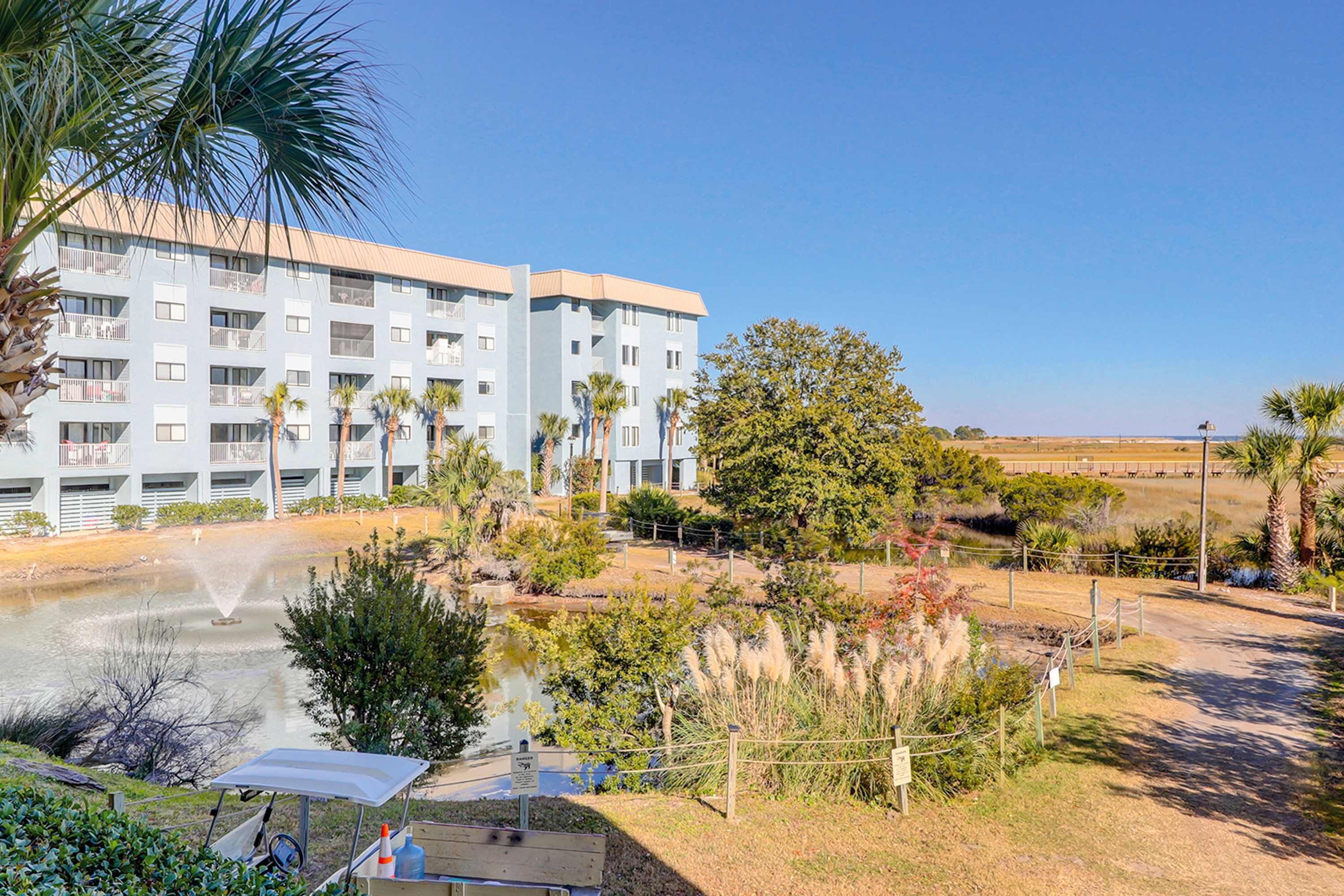 A hotel with a pool, palm trees, and a clear sky.