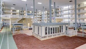 Ein mehrgeschossiges Hotelinneres mit einem zentralen Atrium, mehreren Balkonen und einer kleinen Außenanlage mit einem Gazebo.