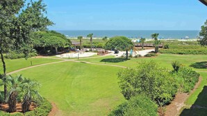 Un césped cuidado, un parque infantil y vista al océano.